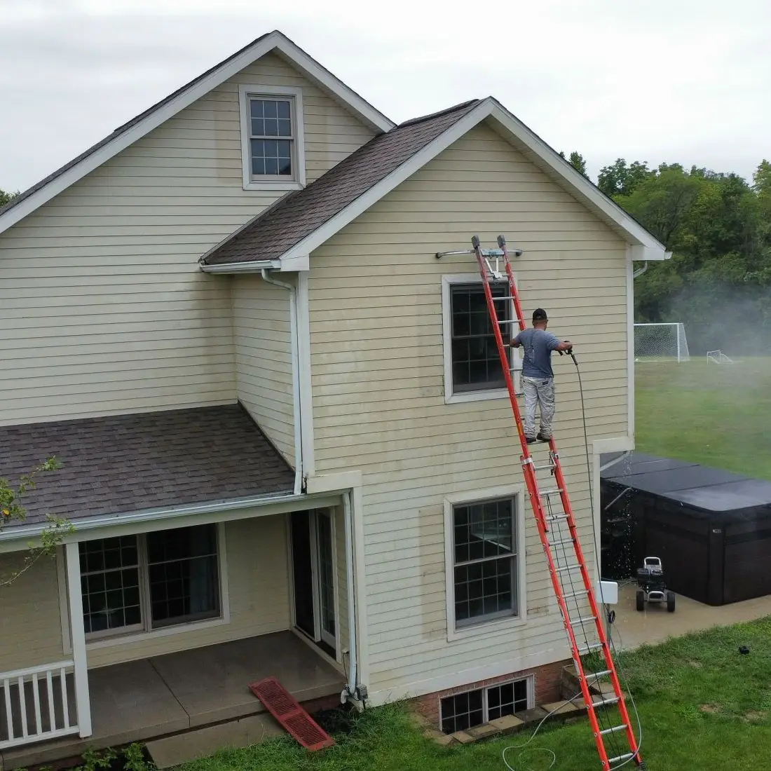 Huinac Painting crew member on a ladder painting an exterior in Northwest Ohio